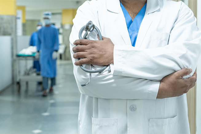 Senior oncologist at Vasavi Hospitals standing with stethoscope in oncology department.