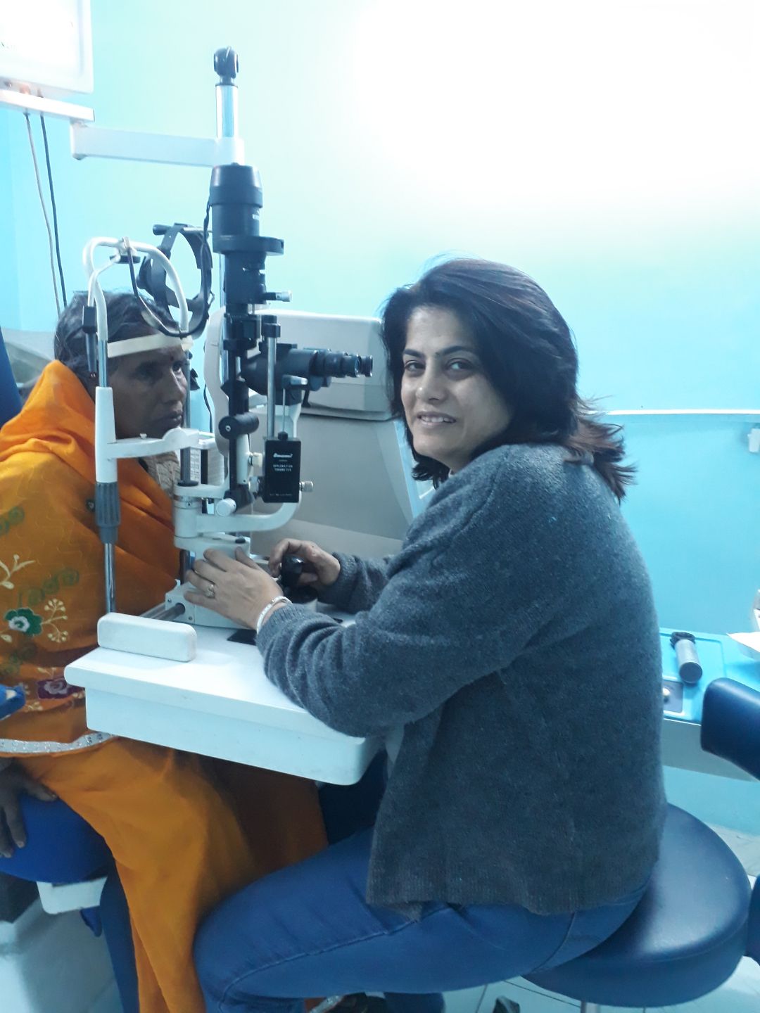 Ophthalmologist performing eye checkup for elderly woman using slit lamp.
